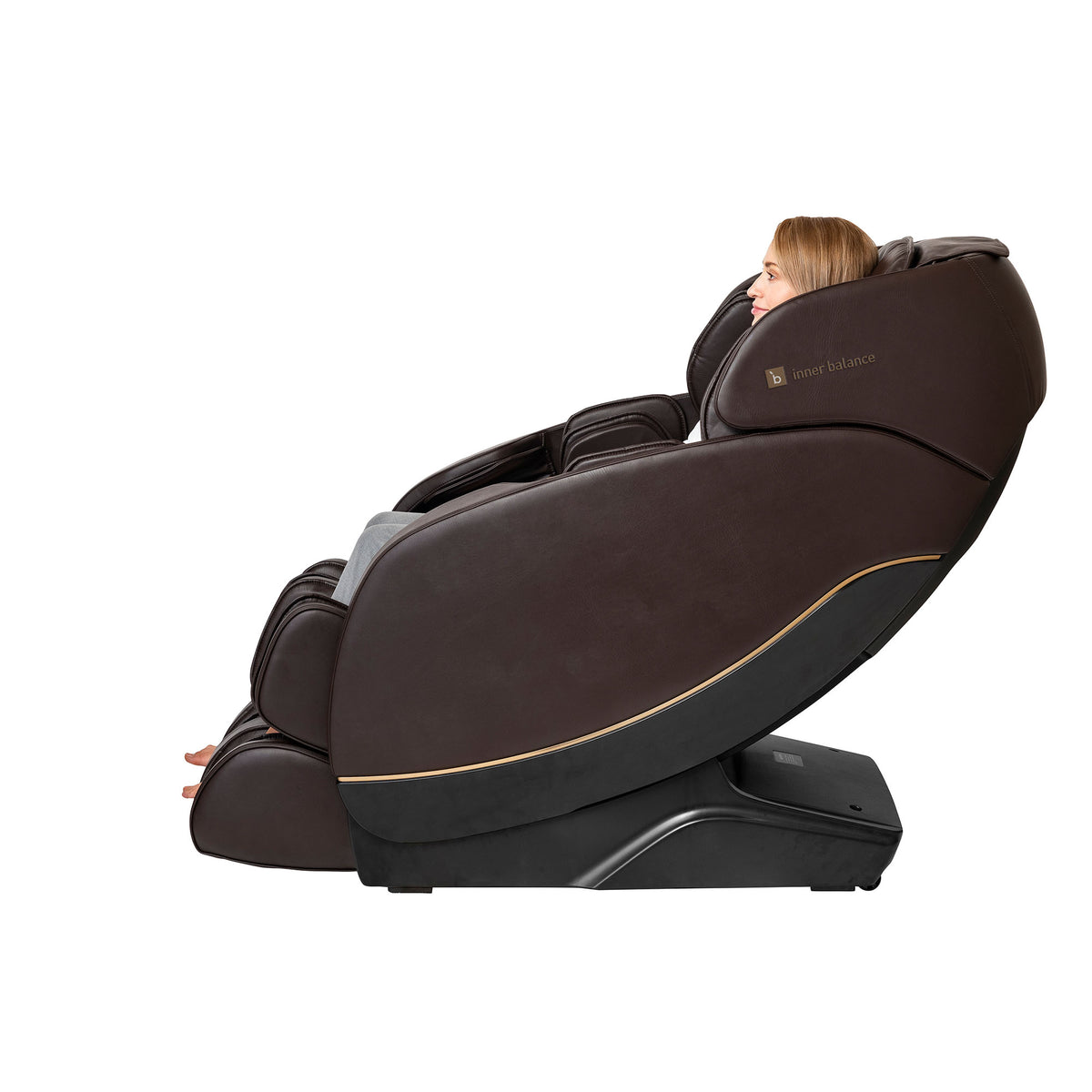 Side view of a woman sitting up-right in the Inner Balance Wellness Jin 2.0 Massage Chair in brown leather with gold trimming
